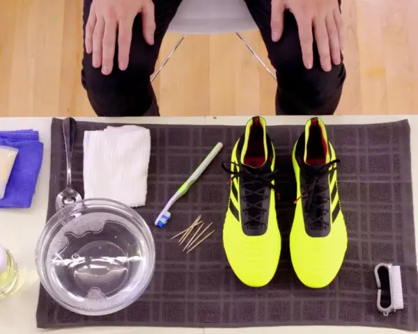 Kit per pulire le scarpe Adidas gialle: spazzolino, acqua saponata, panni e crema.