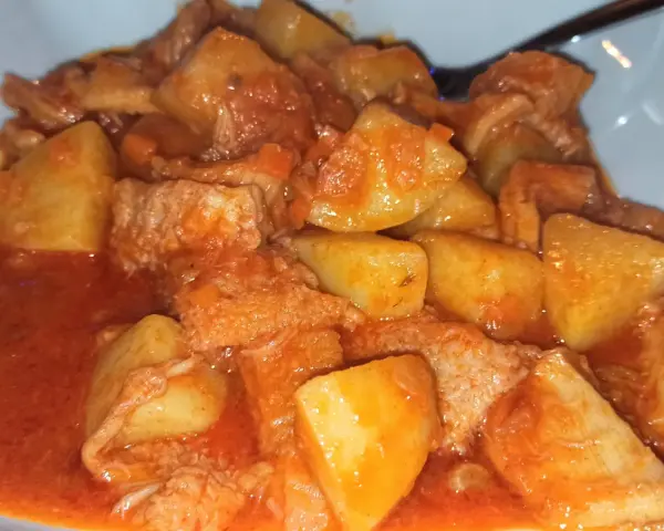 Un piatto fumante di trippa con patate, un classico della cucina italiana, condito con un sugo rosso saporito.