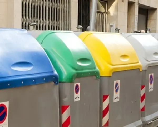 Fila de contenedores de reciclaje de Ecoembes en la calle: azul, verde, amarillo y grises.