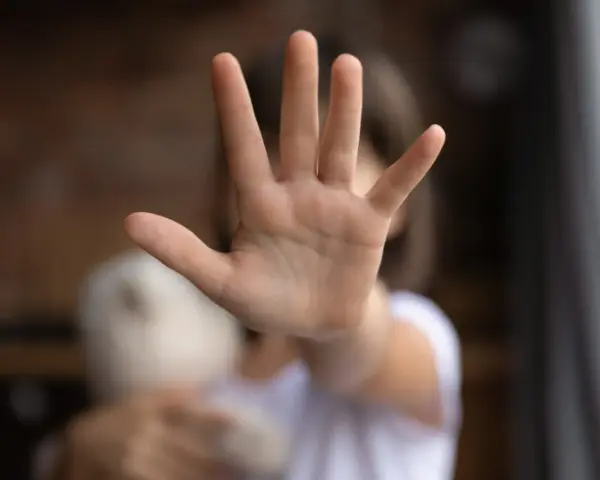 Main d'enfant tendue en signe d'arrêt, tenant une peluche.