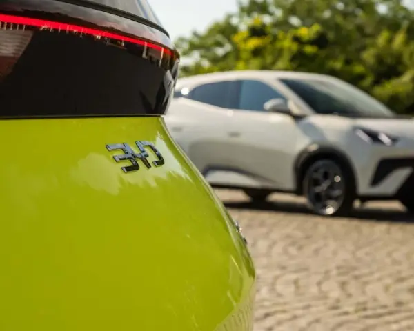 Jasnozielony samochód elektryczny BYD z napisem "310" na klapie bagażnika, w tle biały samochód.