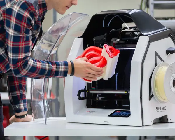 Inżynier wyjmuje z drukarki 3D skomplikowany element, pokazując potencjał druku 3D w przemyśle.