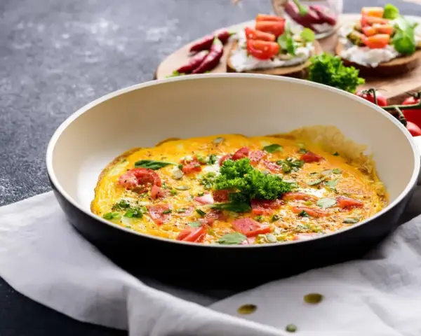 Pyszny omlet z pomidorami i ziołami na patelni, idealny na śniadanie w stylu dieta low carb.