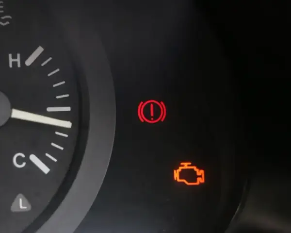 Kontrolka silnika świeci się, wskazując błąd DTC P0010 w Renault. Obok świeci się kontrolka hamulca ręcznego.