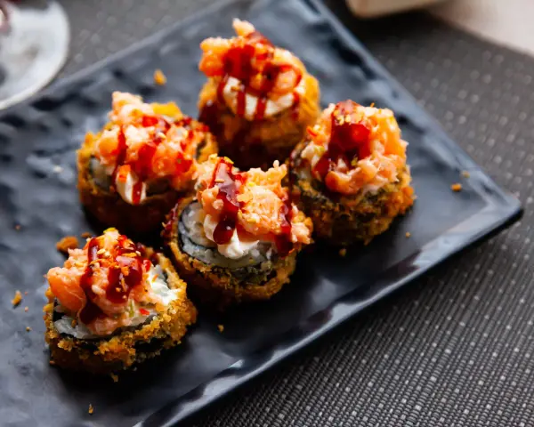 Pięć kawałków sushi w tempurze z łososiem i sosem, idealne na przekąskę.