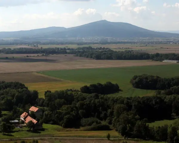 Widok na górzystą okolicę obok Wrocławia z polami, lasami i kilkoma domami.