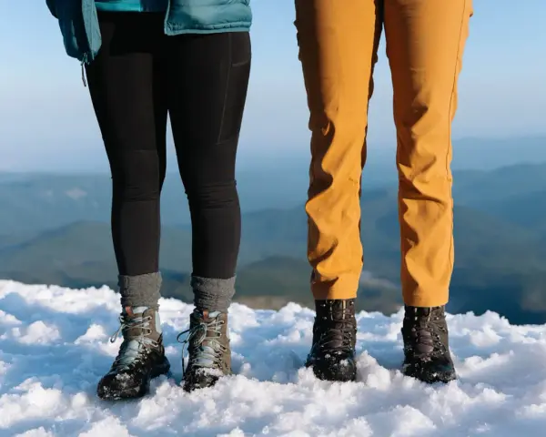 Dwie pary solidnych butów trekkingowych, niczym nowoczesne walonki, stoją na śniegu.