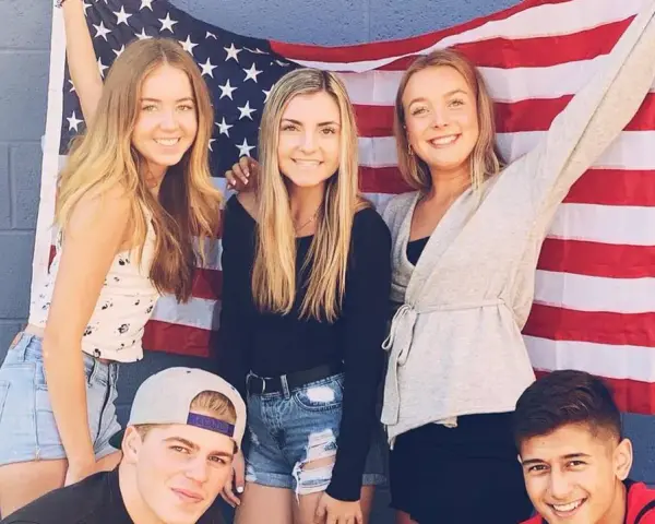 Freunde feiern ihr High School Jahr in den USA vor einer amerikanischen Flagge.