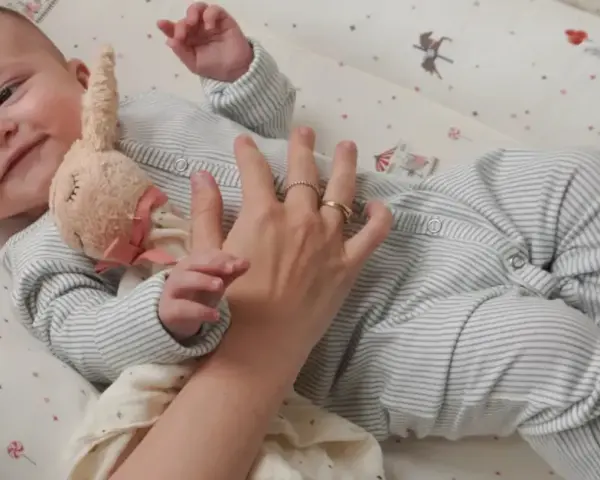 Uroczy niemowlak w pajacyku leży w łóżeczku. Dowiecie się, jak ubrac dziecko do spania, by było mu wygodnie.