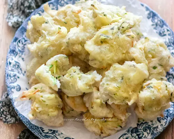 Frittelle di zucchine dolci, dorate e croccanti, servite su un piatto decorato. Un'esplosione di sapore!