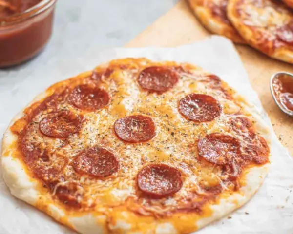 Pyszna pizza z tortilli na patelni, z serem i pepperoni, obok sos w miseczce.