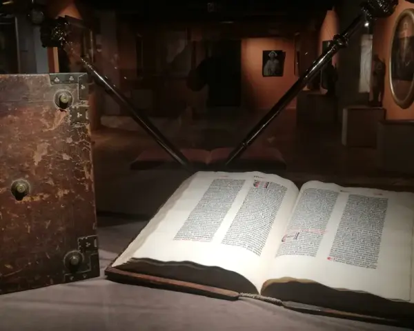 W muzeum diecezjalnym w Pelplinie eksponaty takie jak stary, oprawny księgozbiór i otwarta księga z tekstem przyciągają wzrok zwiedzających.