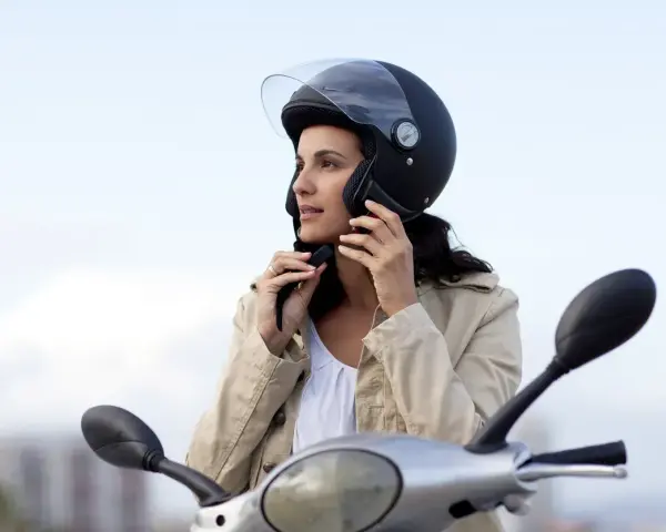 Donna con casco da moto nero, pronta a partire. Non è un luogo dove si buttano i caschi da moto, ma un simbolo di sicurezza.
