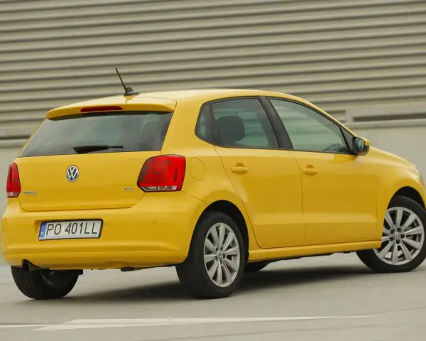 Żółty Volkswagen Polo widziany z tyłu, z widocznym tylnym światłem i tablicą rejestracyjną.