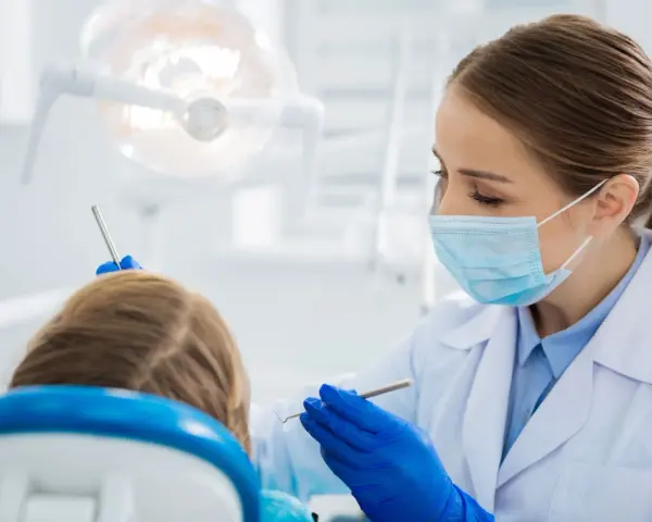 Dentystka bada uśmiech dziecka, by wykluczyć zapalenie dziąseł.