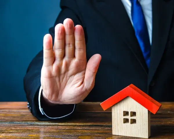Main tendue, un homme en costume bloque une petite maison. Mon ex refuse la désolidarisation, le bien reste bloqué.