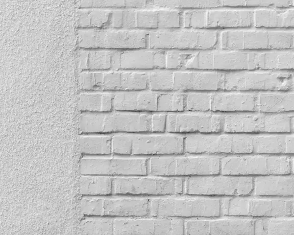 Mur blanc texturé à gauche, briques blanches à droite. Idéal pour un devis de prix piquage et rejointoiement.