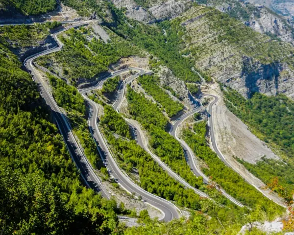 W serpentynach albania trasa pnie się po stromych zboczach gór, otoczona bujną zielenią.