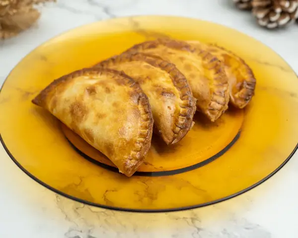Empanadillas doradas y crujientes, recién hechas en freidora de aire, servidas en plato ámbar.