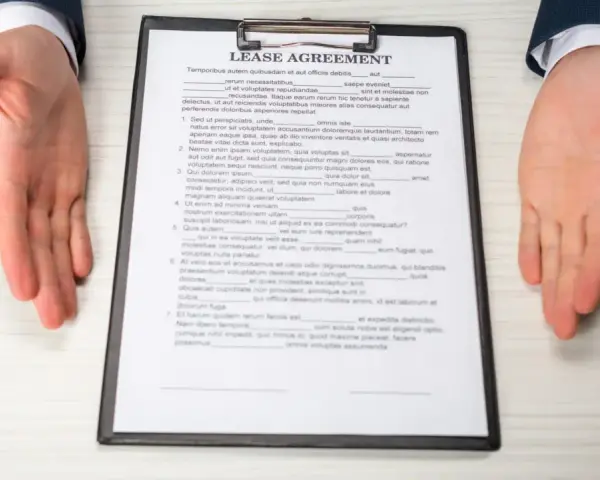 Dłonie wyciągnięte nad dokumentem "Lease Agreement" i długopisem.