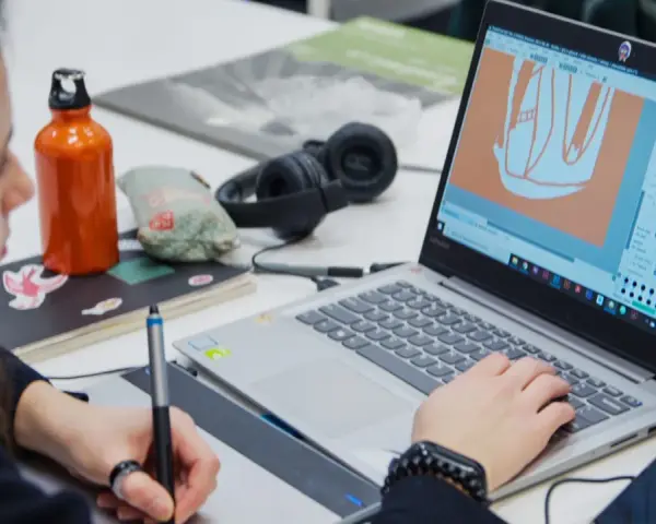 Studentka na studiach grafika Warszawa tworzy projekt na laptopie, używając tabletu graficznego.