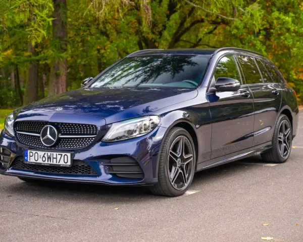 Granatowy Mercedes C klasa W205 kombi zaparkowany na tle jesiennego lasu.