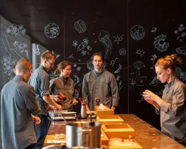 Une série de photos montrant une équipe en cuisine, devant un mur noir décoré de dessins scientifiques et floraux.