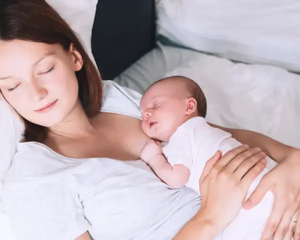 Matka śpi z dzieckiem przy piersi, doświadczając piękna laktacji.