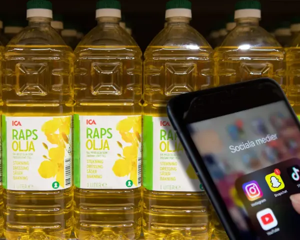 En hand håller upp en mobil med sociala medier-appar. Bakom syns rader av rapsoljeflaskor, där en del anser att rapsolja är farligt.