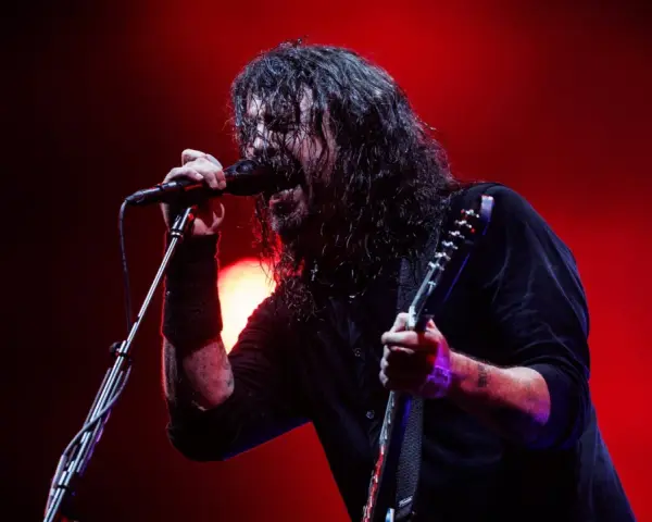 Dave Grohl z Foo Fighters na koncercie, śpiewający do mikrofonu i grający na gitarze.