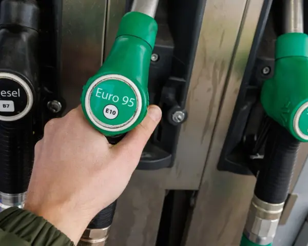 Dłoń trzymająca zielony pistolet z napisem "Euro 95 E10" przy dystrybutorze paliwa. Idealny wybór dla silnika 1.3 multijet.