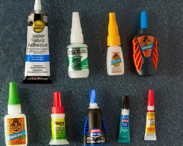 A collection of super glue bottles, including Gorilla Glue and Krazy Glue, are laid out for a comparison of bondic vs super glue.