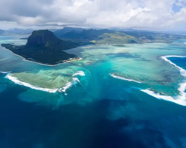 Majestatyczny Le Morne Brabant góruje nad turkusową laguną Mauritiusa. Woda mieni się odcieniami błękitu i zieleni, a białe fale rozbijają się o rafę.