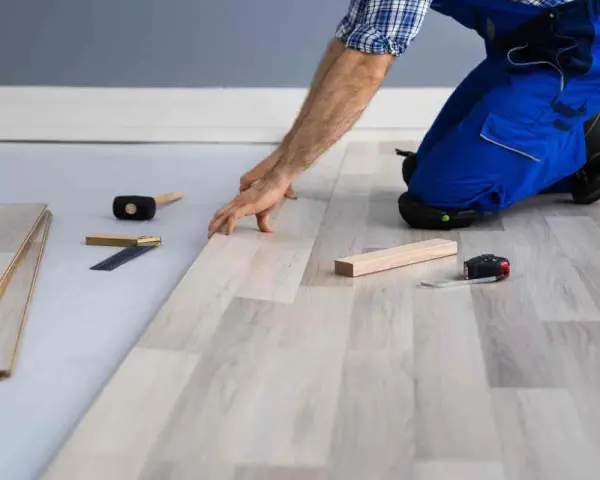 Installazione di un nuovo pavimento in laminato, un passo fondamentale per come isolare il pavimento dal freddo. Attrezzi da lavoro a portata di mano.