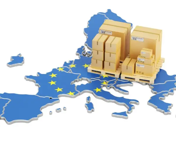 Cajas apiladas sobre palets, sobre un mapa de la Unión Europea con estrellas amarillas. Representa la logística y el comercio, y te preguntas: ¿qué es el VAT en este contexto?