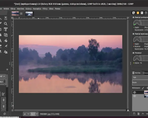 Mglisty poranek nad rzeką, edytowany w **GIMP 2.10**. Widać odbicie drzew w wodzie i wschód słońca.