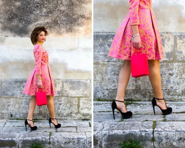 Elegancka stylizacja: jakie buty do różowej sukienki? Czarna, wysoka szpilka idealnie komponuje się z wzorzystą kreacją i torebką.