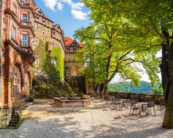 Zamek Książ i okolice: taras z fontanną i stolikami pod drzewami, idealne miejsce na relaks. Warto zobaczyć tę architekturę.