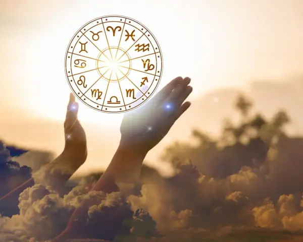 Dłonie unoszą koło zodiaku, symbolizując drogę do tego, jak obliczyć numer astrologiczny.