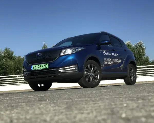 Niebieski SUV Seres 3 zaparkowany na zewnątrz, z widocznym logo i napisem.