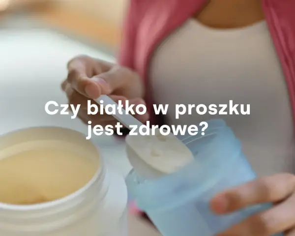 Dłoń nabiera miarkę białka w proszku z dużego pojemnika. Czy białko w proszku jest zdrowe?