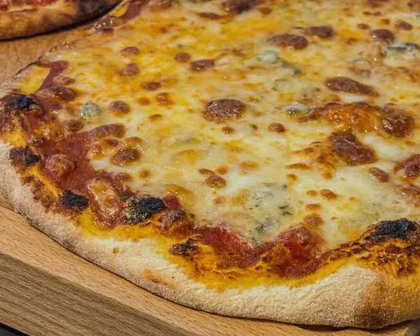 Eine köstliche quattro formaggi Pizza mit geschmolzenem Käse und knusprigem Rand auf einem Holzbrett.