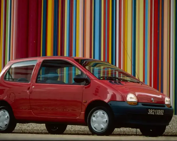 Renault Twingo 1 rouge devant un mur de bandes colorées verticales.