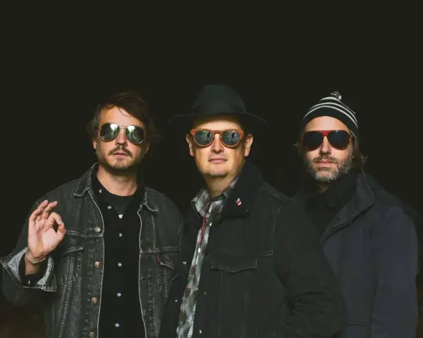 Trois hommes, lunettes de soleil, chapeau, bonnet. Ils ont l'air cool, pas comme des zombies.