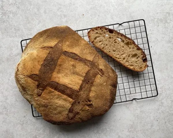 Chleb pszenno orkiszowy, świeżo upieczony, z chrupiącą skórką i puszystym wnętrzem, czeka na kromkę.