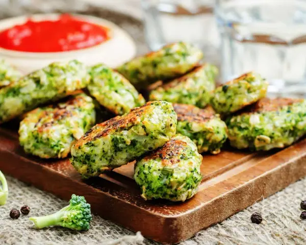 Deliciosas bolitas de brócoli, perfectas para tus recetas con brócoli. Servidas con salsa roja y un toque de pimienta.