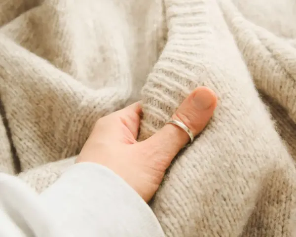 Mięciutki, beżowy, sfilcowany sweter z wełny, który otula dłoń.