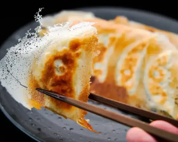 Chrupiące gyoza z delikatną, koronkową skórką, podniesione pałeczkami. Idealny przepis na gyoza!