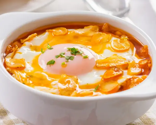Sopa castellana en cuenco blanco con huevo escalfado y picatostes.