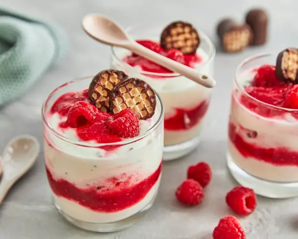 Schokokuss Dessert mit Mascarpone, Himbeeren und Schokowaffel-Keksen in Gläsern, garniert mit frischen Himbeeren.